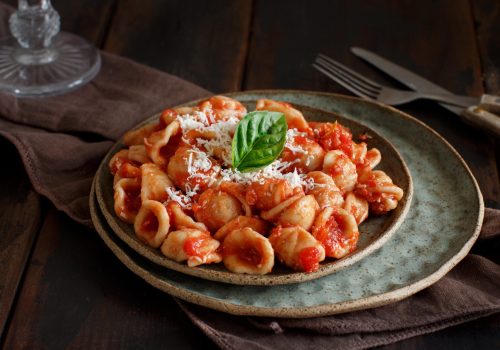 South italian  pasta orecchiette with tomato sauce and cacioricotta cheese close up on a dark table